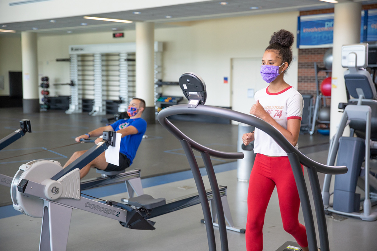 A person wearing a mask and running on a treadmill